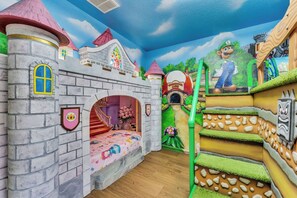 A child's playroom with a castle-themed mural, a bed, and a staircase. - Castle Bunks & Viking Ship, Pool+Spa, 8 Min Disney (Kissimmee)