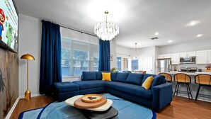Ein modernes Wohnzimmer mit einer Eckcouch, einem runden Couchtisch und einer Pendelleuchte.