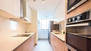 A modern kitchen with stainless steel appliances, wooden cabinets, and a central island. - ✶ Kotosh Residence ✶ LUXURY Best Location | Piano (Miraflores)
