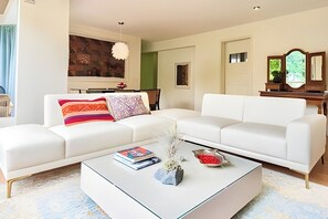 Uma sala de estar moderna com um sofá branco, uma mesa de centro de vidro e um quadro na parede.