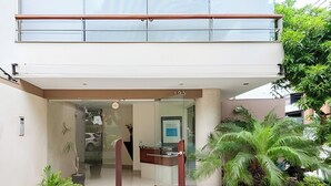 A modern building entrance with a glass door, a number '125' above it, and a small garden with potted plants. - ✶ Kotosh Residence ✶ LUXURY Best Location | Piano (Miraflores)