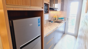 Een moderne keuken met houten kastjes, een roestvrijstalen koelkast en een marmeren aanrecht.