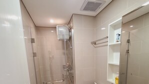 A modern bathroom with a glass-enclosed shower, a white toilet, and a sink with a mirror above it. - Apartment Lincoln Podomoro Delipark (Medan)