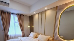 A modern bedroom with a large bed, a bedside table, a mirror, and an air conditioning unit. - Apartment Lincoln Podomoro Delipark (Medan)