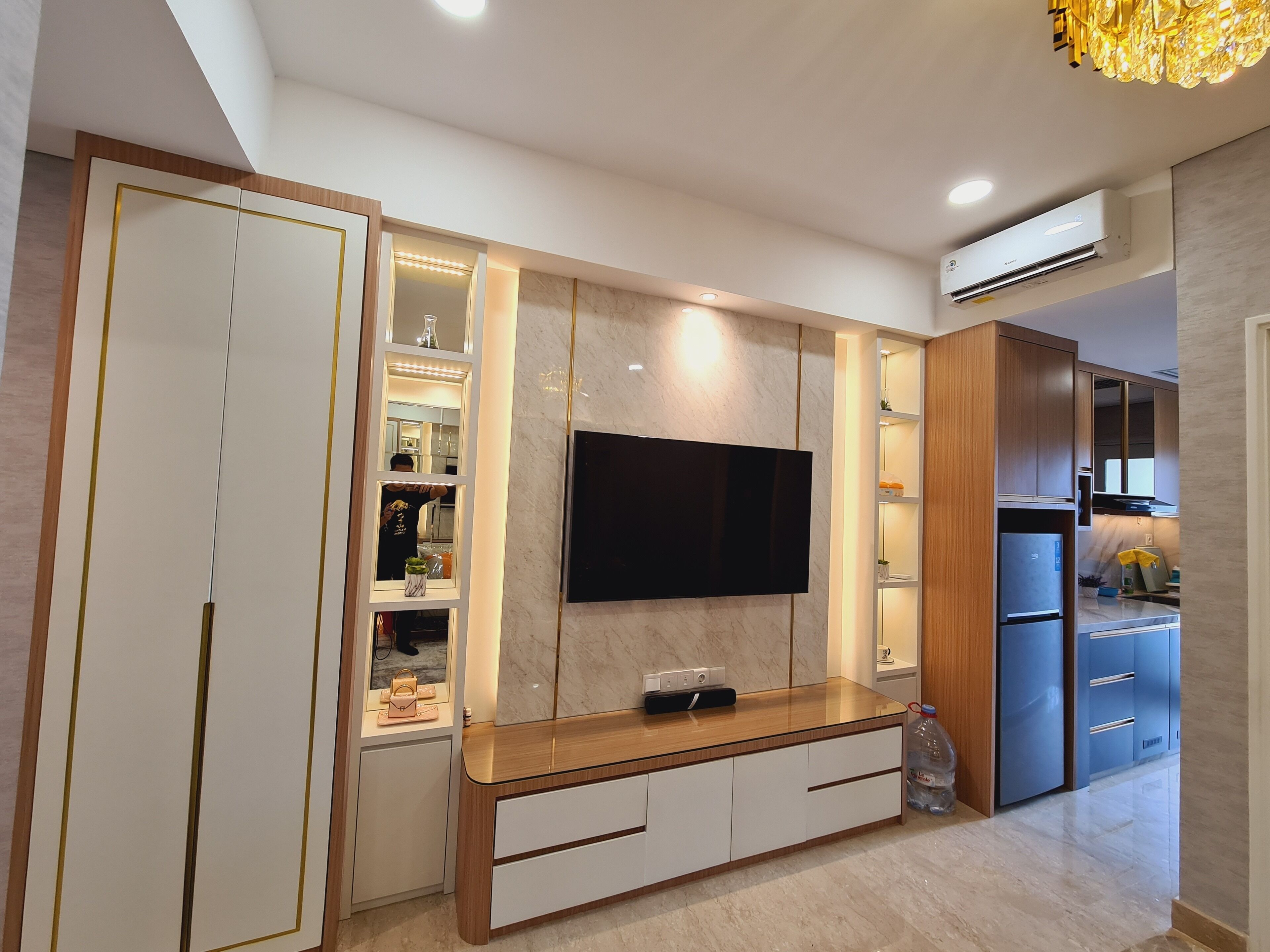 A modern kitchen with a built-in TV, wooden cabinets, and a marble backsplash.