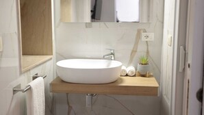 Een badkamer met een witte wastafel, een houten aanrechtblad en een spiegel erboven.
