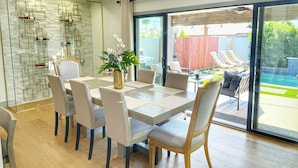 Een eetgedeelte met een glazen scheiding, een tafel met stoelen en uitzicht op de achtertuin.