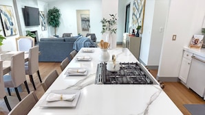 Een moderne keuken met een marmeren aanrecht, een gasfornuis, en een eethoek met vier stoelen rondom een tafel.