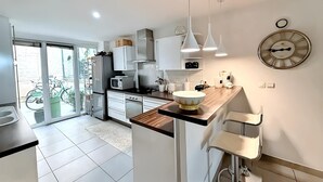 A modern kitchen with white cabinets, a wooden countertop, and a large wall clock.