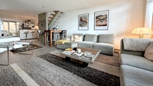 A modern living room with a sofa, coffee table, and a staircase leading to an upper level.
