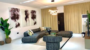 A modern living room with a sectional sofa, a round coffee table, and abstract wall art. - 2-bedroom apartment in serene Lekki with pool (Lekki)