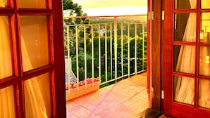 An open wooden door leading to a balcony with a view of a green landscape and a clear sky. - Pousada Pink Village  (Campos do Jordão)