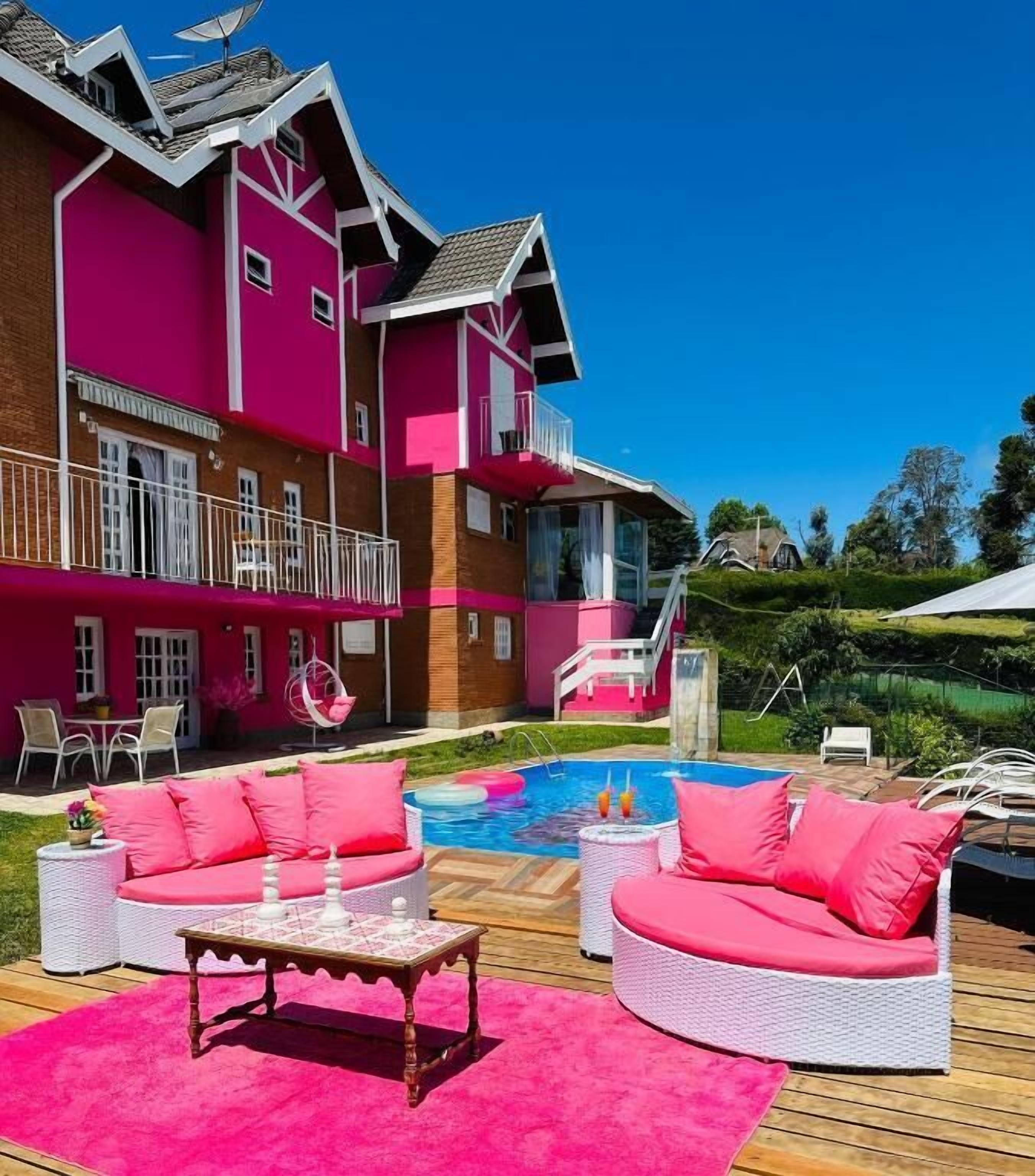 A pink house with a pool, outdoor furniture, and a deck.