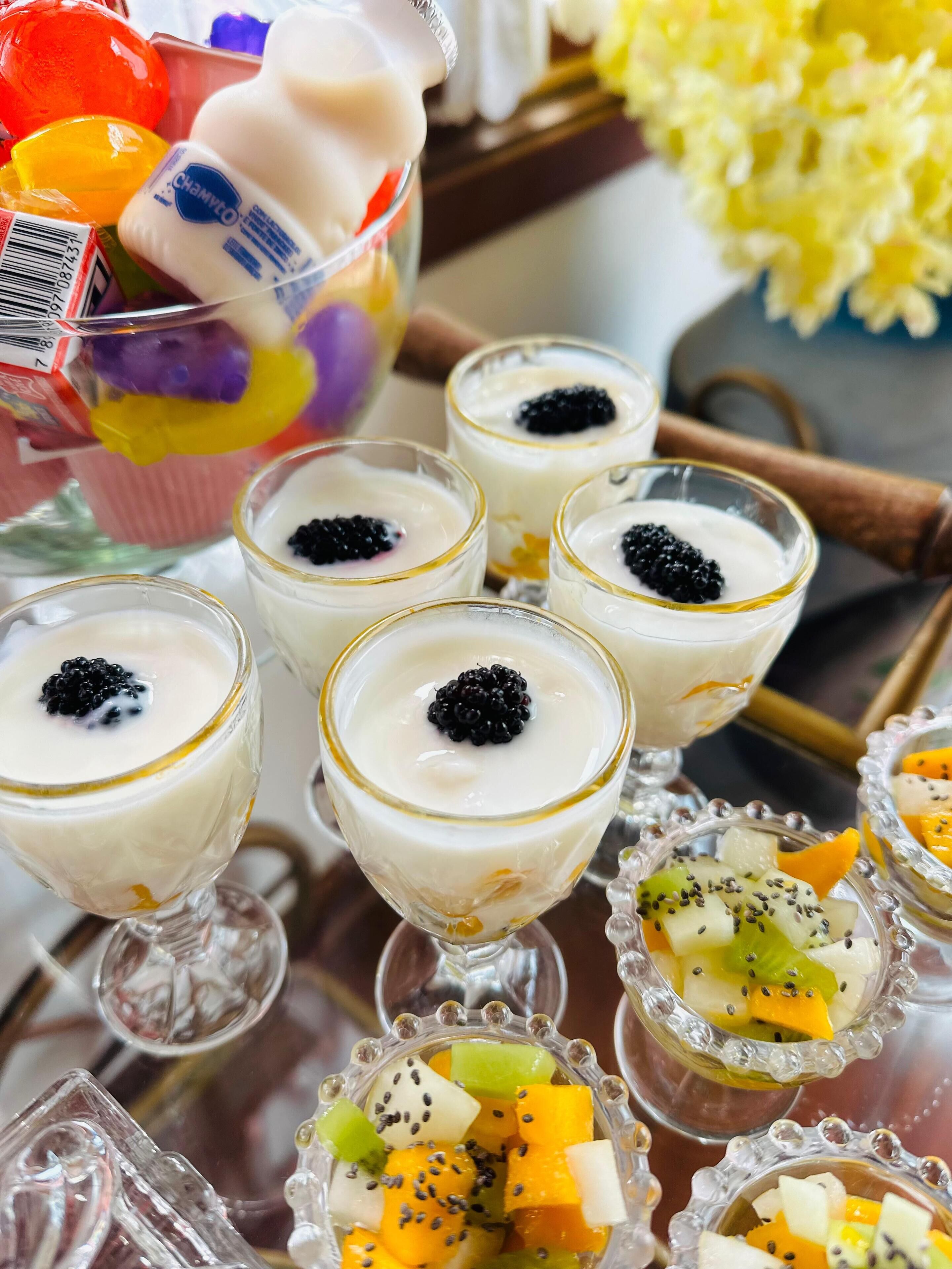 Verschiedene Desserts, darunter Joghurtbecher mit Früchten und eine Schüssel mit Obst und Joghurt.