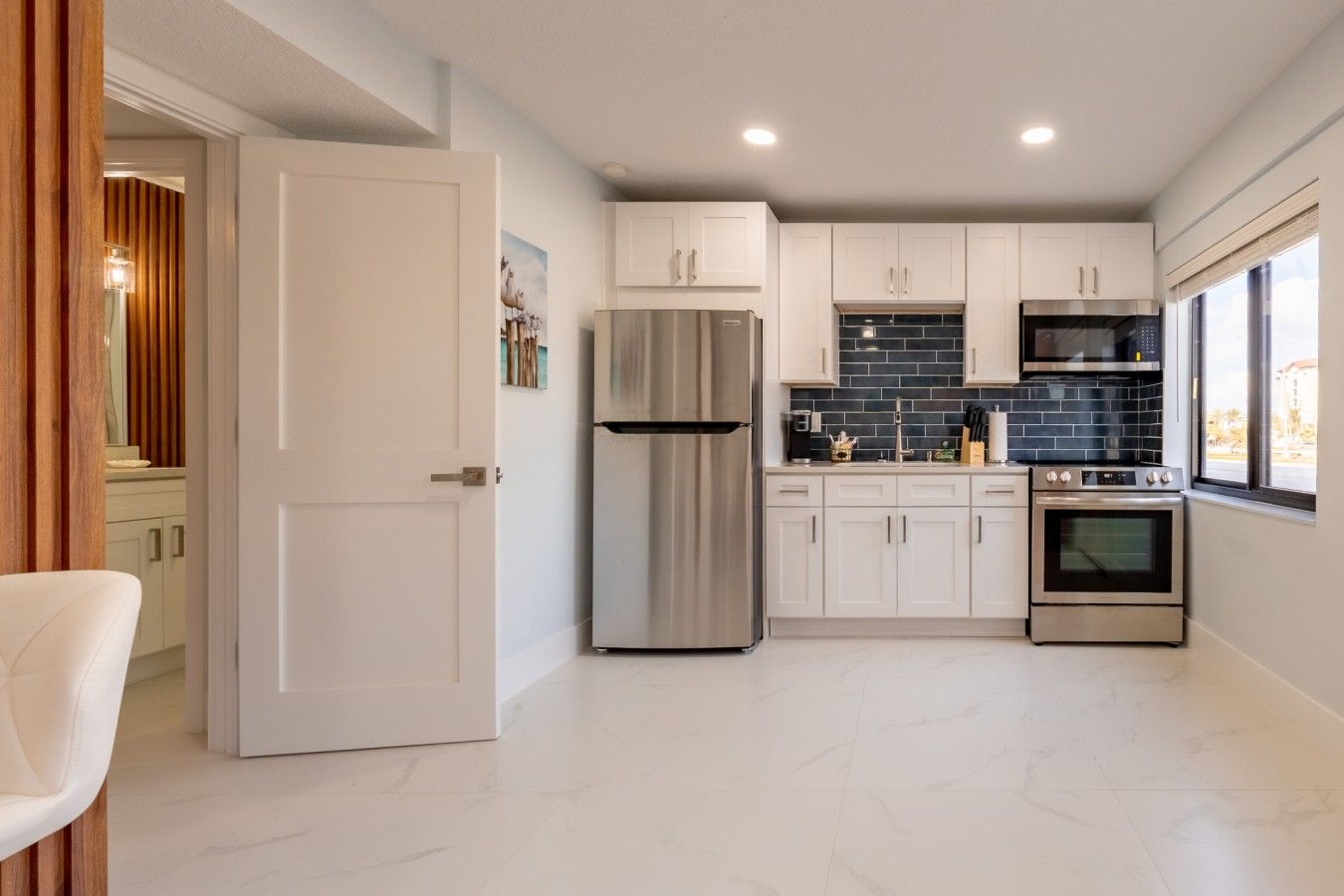 Een moderne keuken met witte kastjes, roestvrijstalen apparatuur en een backsplash van zwart tegels.