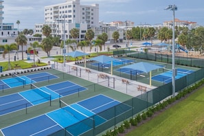 Et tennisanlæg med flere baner, siddepladser og en legeplads.