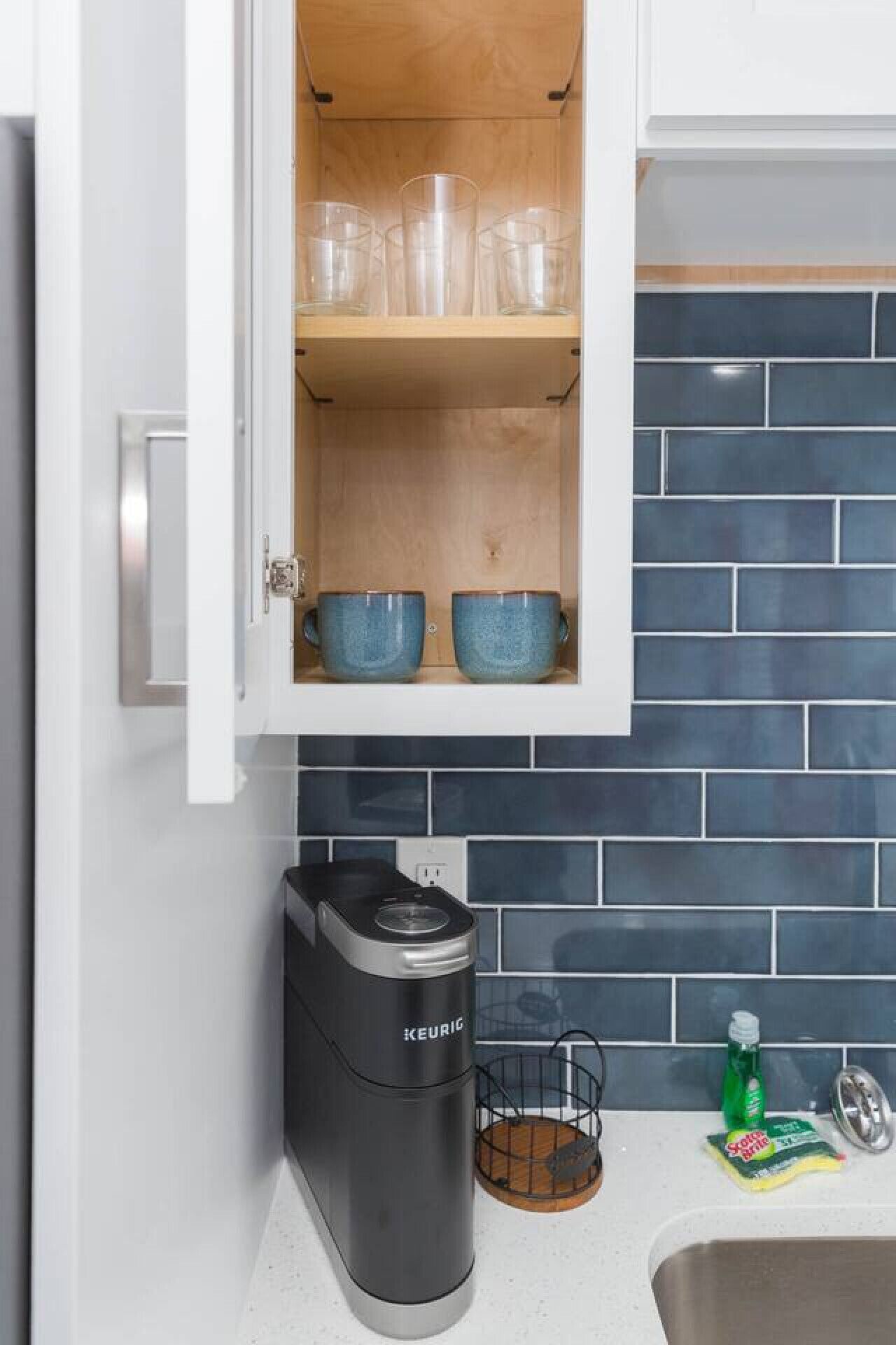 Eine Küche mit Einbaukorpus, einer Kaffeemaschine und einer gefliesten Spritzschutzwand.