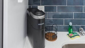 Eine Küche mit Einbaukorpus, einer Kaffeemaschine und einer gefliesten Spritzschutzwand.