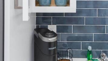 Eine Küche mit Einbaukorpus, einer Kaffeemaschine und einer gefliesten Spritzschutzwand.