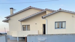 A two-story house with a tiled patio, a chimney, and a gated entrance. - The house on the Atlantic Ocean Portugal (Praia do Pedrogao)