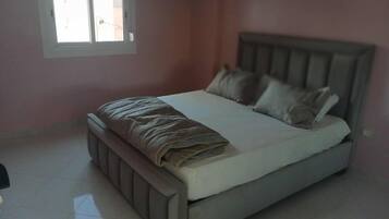 Une chambre à coucher avec un lit, des oreillers et une fenêtre.