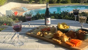 A table set outdoors with a bottle of wine, glasses, and a charcuterie board. - Charm and relaxed living in Lorgues: Villa Tira, swimming pool and 3300 m2 garden (Lorgues)