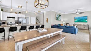 Eine moderne Küche mit weißen Schränken, einem Edelstahlkühlschrank und einem Essbereich mit Holztisch und Bänken.