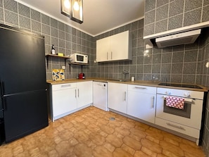 A kitchen with a black refrigerator, white cabinets, a microwave, and a stove.