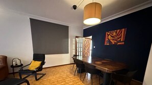 A room with a wooden floor, a dining table with chairs, a sofa, a small table with a lamp, and a painting on the wall. - 7 Bedroom house w/ 2 kitchens (Vila Nova de Gaia)