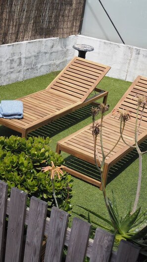 Un patio con dos sillones de madera, una mesita y una planta decorativa.