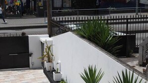A modern building with a tiled walkway and a white wall with palm trees. - 7 Bedroom house w/ 2 kitchens (Vila Nova de Gaia)