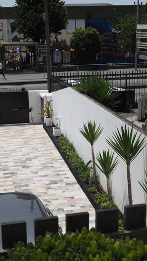 A modern building with a tiled walkway and a white wall with palm trees. - 7 Bedroom house w/ 2 kitchens (Vila Nova de Gaia)
