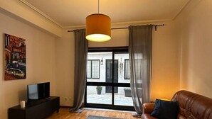 A living room with a brown leather sofa, a grey rug, a black entertainment unit, and a painting on the wall. - 7 Bedroom house w/ 2 kitchens (Vila Nova de Gaia)