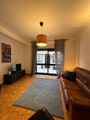 A living room with a brown leather sofa, a grey rug, a black entertainment unit, and a painting on the wall. - 7 Bedroom house w/ 2 kitchens (Vila Nova de Gaia)