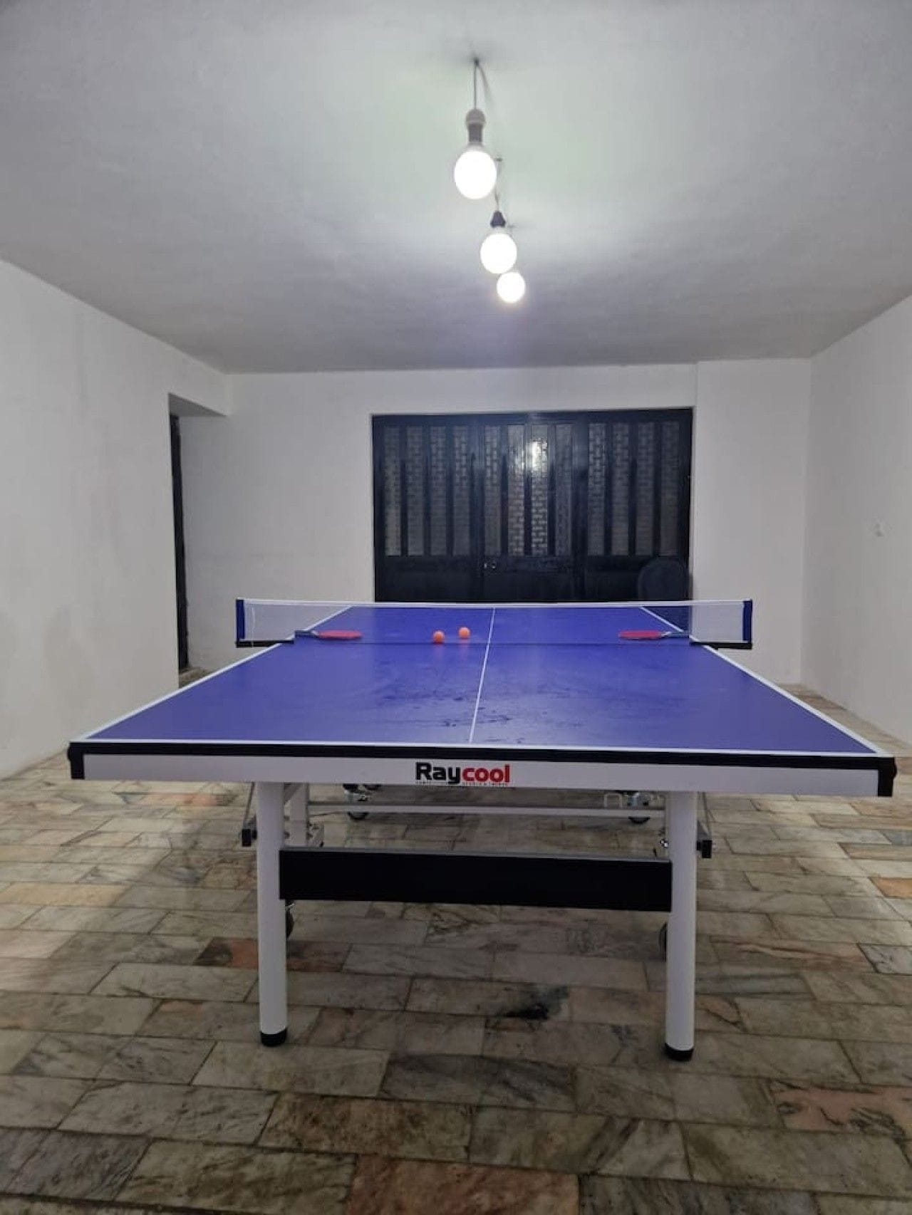 Et ping pong-bord med blå spilleflade og hvide ben, med påskriften 'Raycool'.