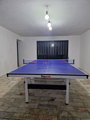 A ping pong table with a blue playing surface and white legs, labeled 'Raycool.'