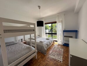 Una habitación con literas, un escritorio, una silla, una ventana con cortinas y una lámpara colgante.
