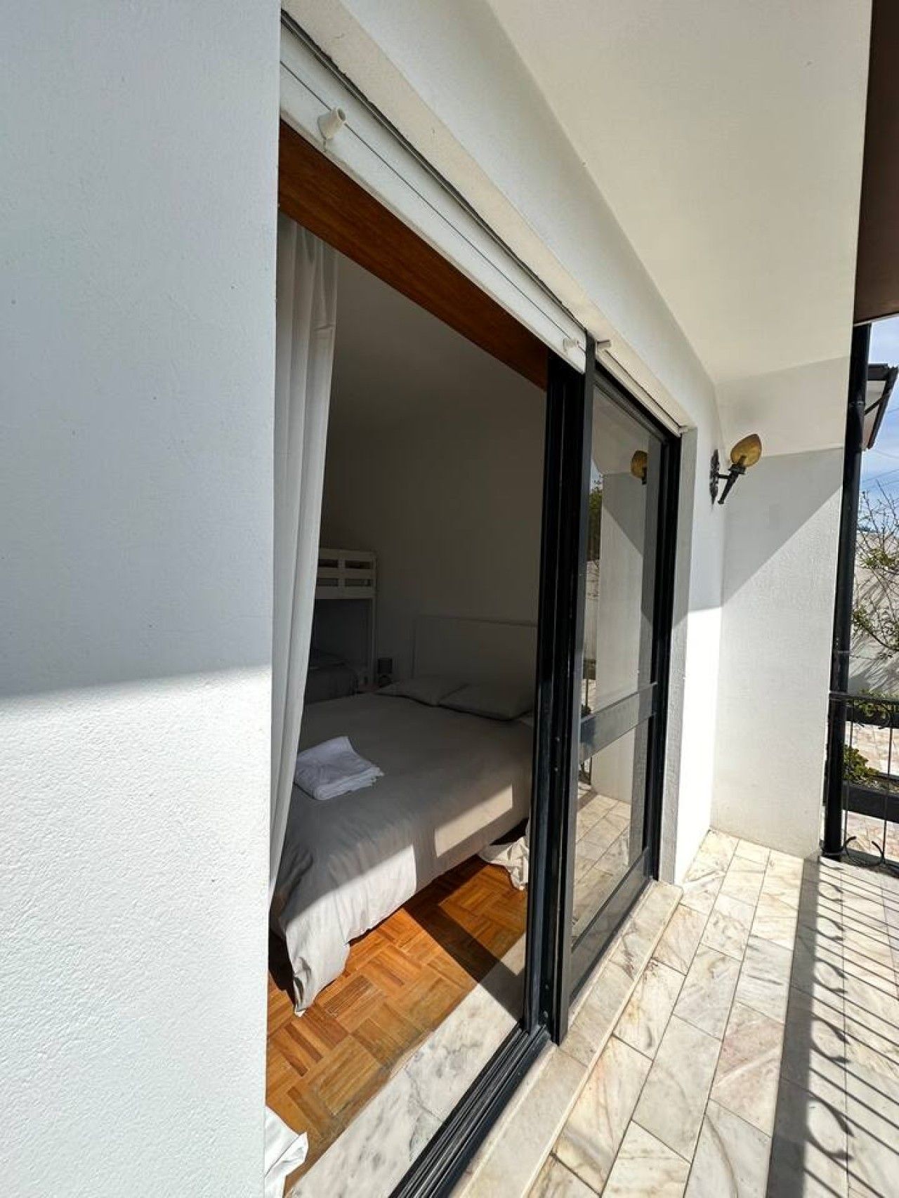 A bedroom with a bed, a window, and a view of the outside.