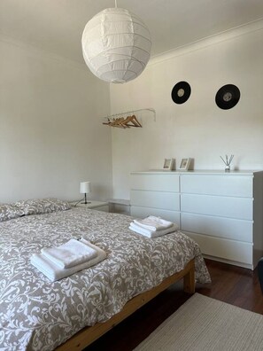 A bedroom with a double bed, a dresser, a hanging light fixture, and wall-mounted decor. - 7 Bedroom house w/ 2 kitchens (Vila Nova de Gaia)