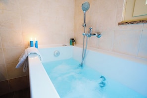 A bathroom with a bathtub filled with water, a handheld showerhead, and a towel hanging on the side. - B&B Quattro Torri (Santa Teresa di Riva)