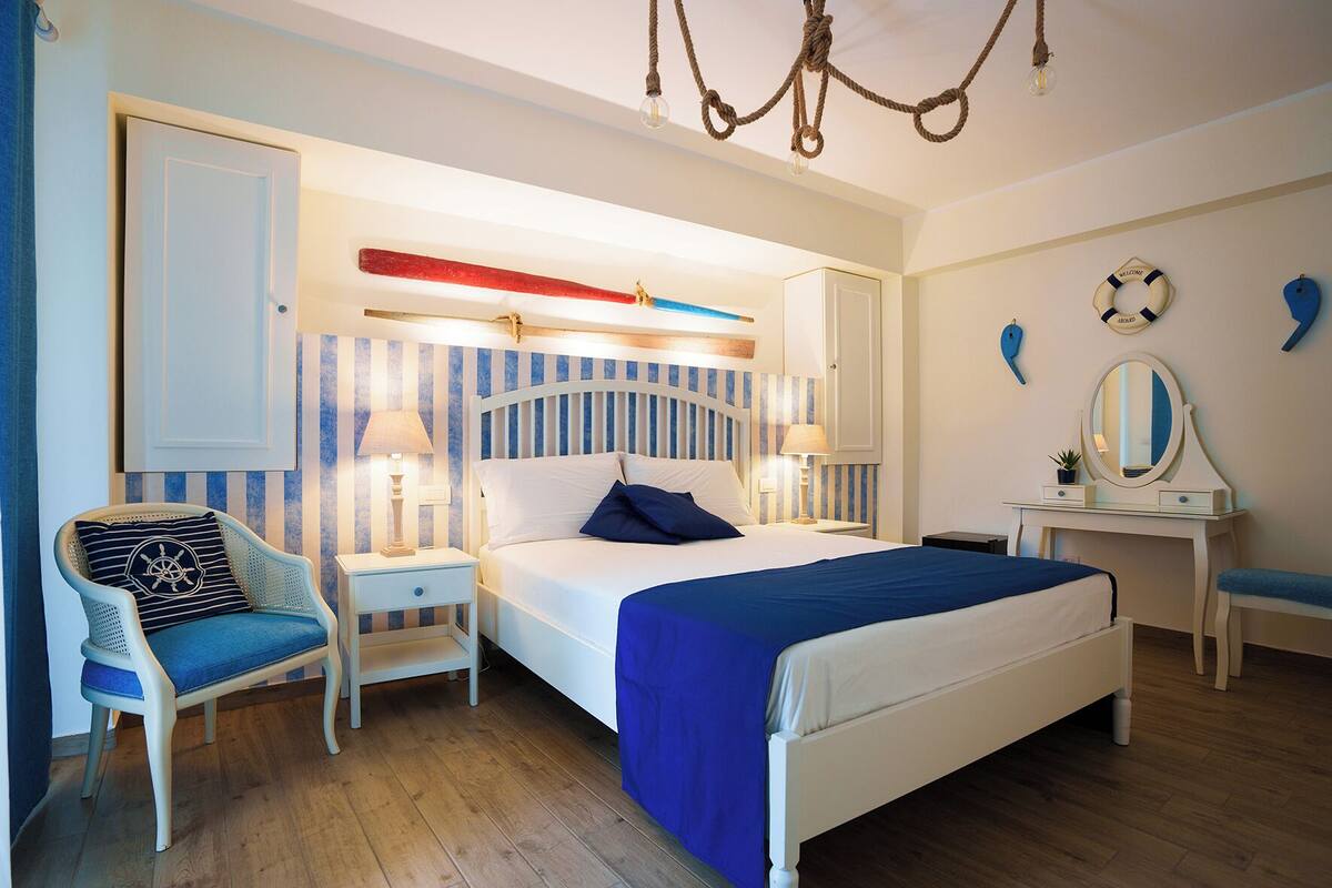 Une chambre à coucher comprenant un lit, des tables de chevet, une chaise, une commode et un lustre.