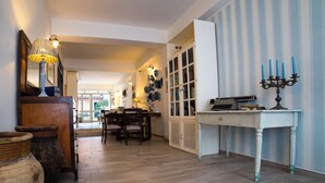 A room with a wooden floor, a dining table with chairs, a white cabinet, and a candelabra on a side table. - B&B Quattro Torri (Santa Teresa di Riva)