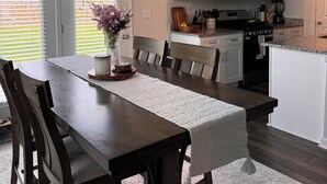 Eine moderne Küche mit weißen Schränken, einer Mikrowelle und einem Essbereich mit einem Holztisch und Stühlen.