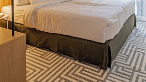 A modern hotel room with a large bed, wooden paneling, a geometric patterned rug, and a large window with curtains. - Marone Suites Budapest (Budapest)
