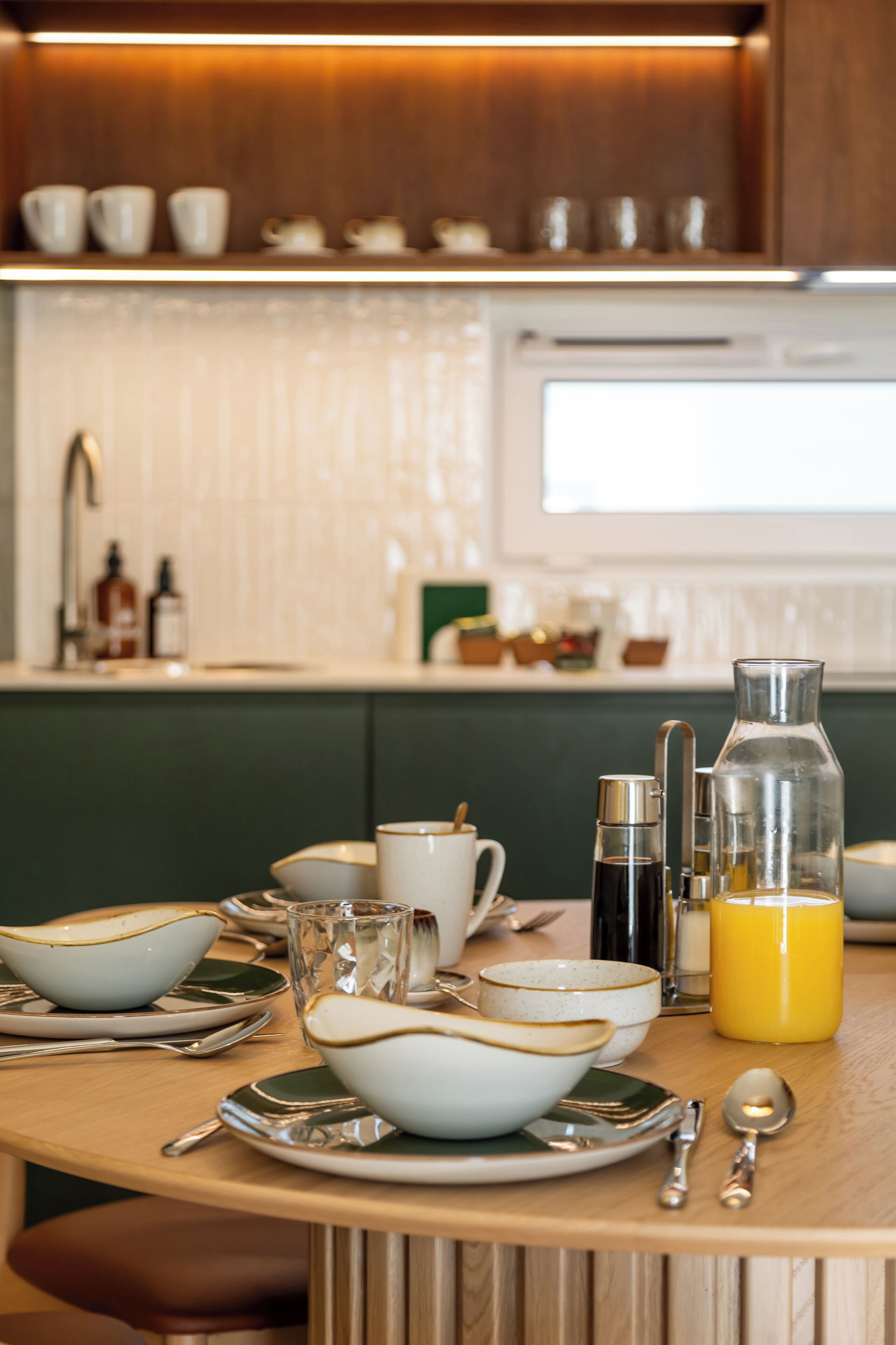 A breakfast table set with bowls, cups, and a glass of orange juice.