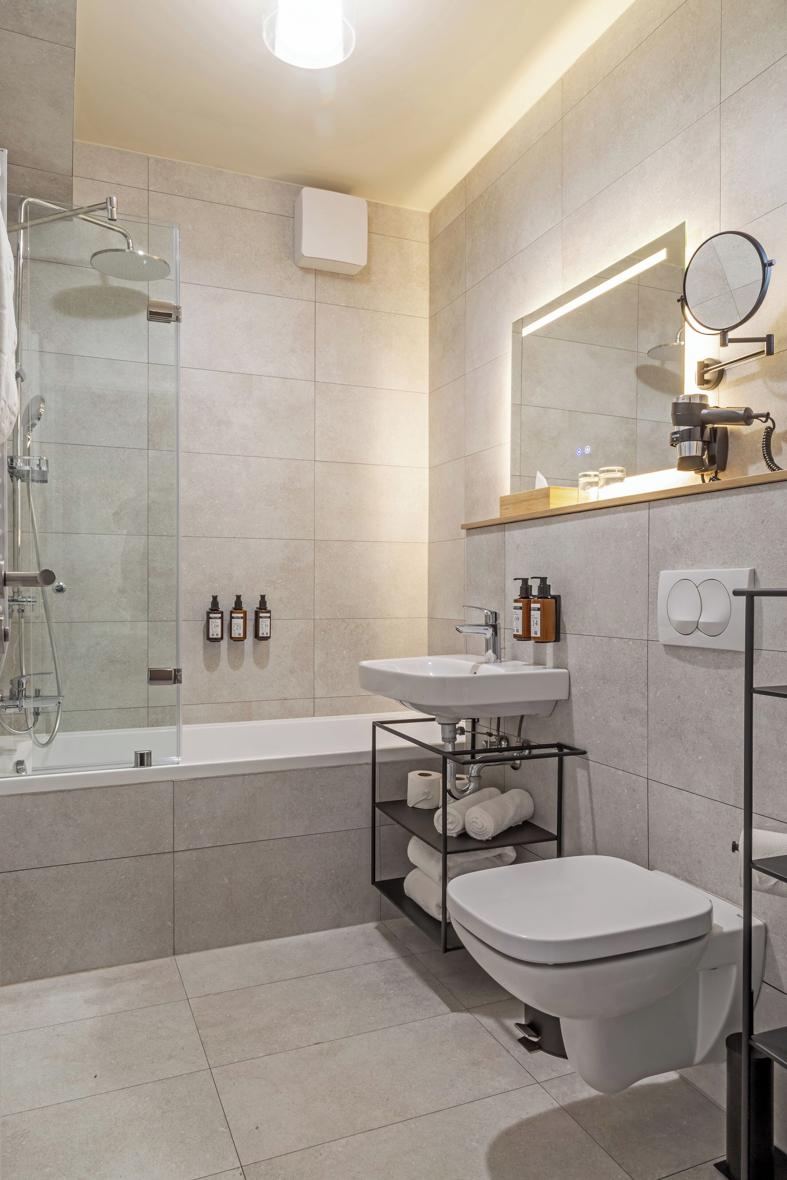 Une salle de bain moderne avec une douche à parois de verre, un lavabo blanc, des toilettes et un miroir au-dessus du lavabo.
