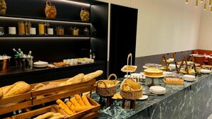 A buffet with various breads and pastries displayed on wooden racks and baskets. - Marone Suites Budapest (Budapest)