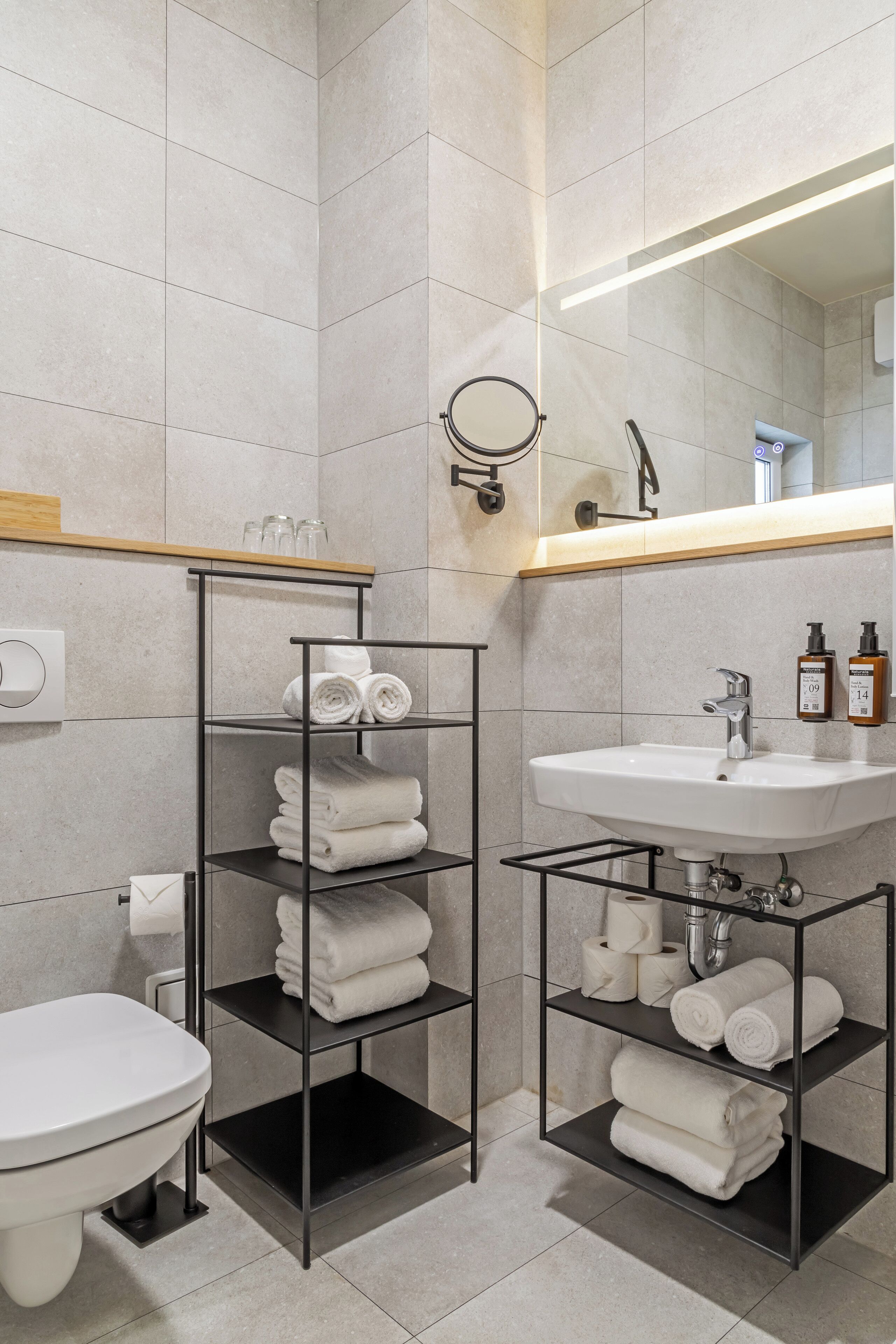 A modern bathroom with a toilet, a sink, and two towel racks.