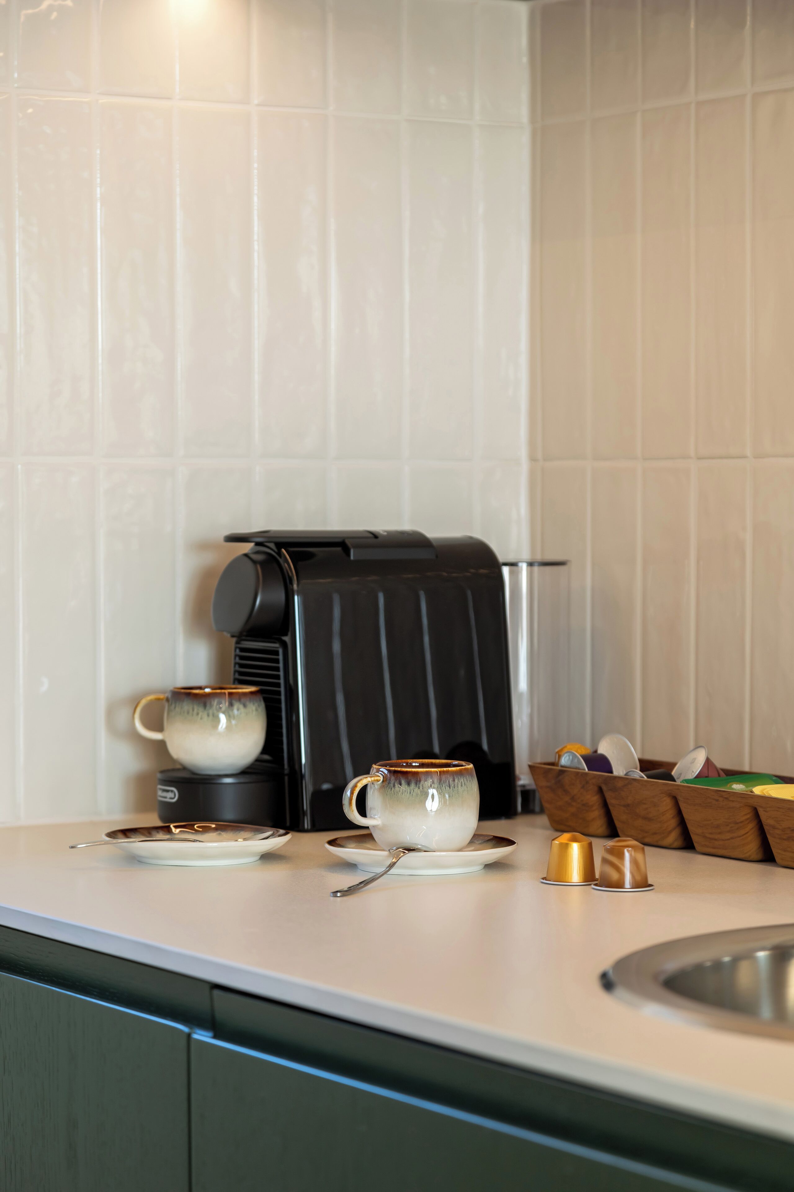 Une cuisine équipée d’une machine à café, de deux tasses et d’un égouttoir à vaisselle.