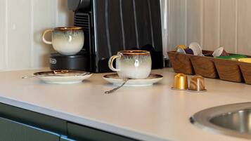 Une cuisine équipée d’une machine à café, de deux tasses et d’un égouttoir à vaisselle.